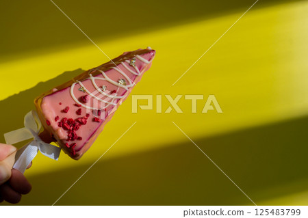 Female hand holding trendy sweet dessert cheesecake on colorful vibrant yellow background. Takeout takeaway present idea. Copy space for advertisement homemade cake bakery treat trend 125483799