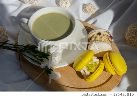 Sweet yellow macaron dessert Cup of green plant based matcha tea latte in cozy morning bed atmosphere. Creative holiday romantic date idea. Herbal prebiotic fiber superfood beverage antioxidant-rich Sweet yellow macaron dessert Cup of green plant based matcha tea latte in cozy morning bed atmosphere. Creative holiday romantic date idea. Herbal prebiotic fiber superfood beverage antioxidant-rich 125483810