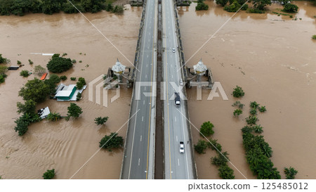 Aerial view of car driving on the bridge while water rising during typhoon Yagi has swept Chiang Rai province of Thailand. Aerial view of car driving on the bridge while water rising during typhoon Yagi has swept Chiang Rai province of Thailand. 125485012