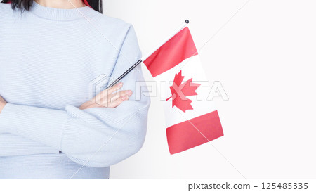 Unrecognized girl student in blue shirt holding small Canadian flag over gray background, Canada day, holiday, vote, immigration, tax, copy space Unrecognized girl student in blue shirt holding small Canadian flag over gray background, Canada day, holiday, vote, immigration, tax, copy space 125485335