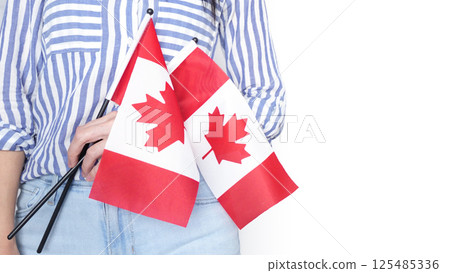 Unrecognized girl student in white blue shirt holding small Canadian flag over gray background, Canada day, holiday, vote, immigration, tax, copy space Unrecognized girl student in white blue shirt holding small Canadian flag over gray background, Canada day, holiday, vote, immigration, tax, copy space 125485336