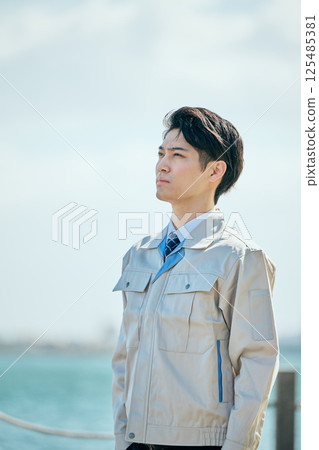 A young man in his 20s wearing work clothes gazing into the distance 125485381