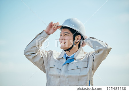 一名 20 多歲的年輕男子穿著工作服，戴著頭盔 125485388
