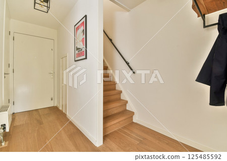 A stylish entrance showcasing modern interior design elements. Features stairs, minimalist decor, and a warm color palette, creating an inviting atmosphere. A stylish entrance showcasing modern interior design elements. Features stairs, minimalist decor, and a warm color palette, creating an inviting atmosphere. 125485592