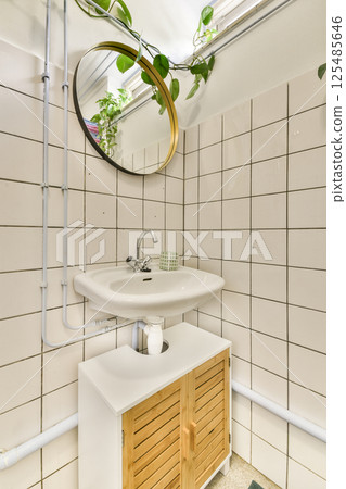 A stylish, modern bathroom featuring a sleek sink, wooden storage, and decorative plants, creating an inviting and fresh atmosphere. 125485646