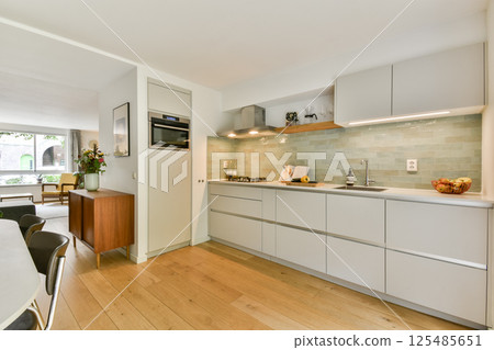 A stylish modern kitchen featuring sleek cabinetry, minimalist decor, and natural light streaming in. The open layout enhances the space's functionality and aesthetic appeal. 125485651
