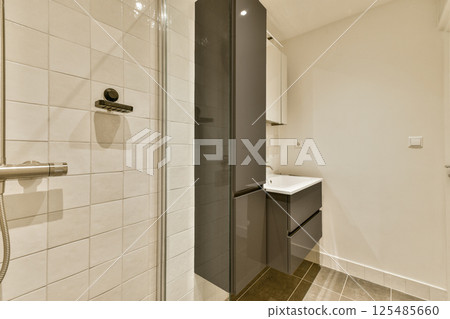 A sleek bathroom featuring contemporary fixtures, including a glass shower and minimalistic cabinetry, showcasing an elegant blend of functionality and style. A sleek bathroom featuring contemporary fixtures, including a glass shower and minimalistic cabinetry, showcasing an elegant blend of functionality and style. 125485660