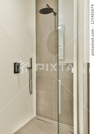 A sleek and contemporary shower room featuring glass panels, modern fixtures, and minimalist design, creating an elegant and functional space for relaxation. 125485674