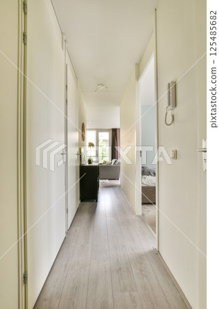 A spacious and well-lit indoor hallway featuring minimalist design elements, light wooden flooring, and doors leading to different rooms. A spacious and well-lit indoor hallway featuring minimalist design elements, light wooden flooring, and doors leading to different rooms. 125485682