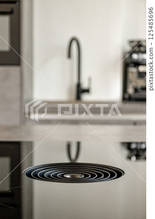 The image showcases a sleek kitchen sink drain with a modern design. Reflections can be seen on the countertop, creating a minimalist look. 125485696