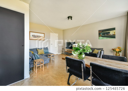 A stylish modern living room featuring comfortable seating, a dining area, and decorative elements, creating a welcoming atmosphere for relaxation and entertainment. A stylish modern living room featuring comfortable seating, a dining area, and decorative elements, creating a welcoming atmosphere for relaxation and entertainment. 125485726