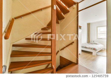An inviting view of a wooden staircase leading to a cozy bedroom, showcasing a blend of modern design and comfort. An inviting view of a wooden staircase leading to a cozy bedroom, showcasing a blend of modern design and comfort. 125485739