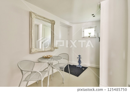 A chic and serene minimalist interior featuring a small seating area with a table and ornamental decor. The soft colors enhance its peaceful atmosphere. 125485750