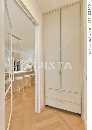 Sleek and elegant interior featuring a modern kitchen with white cabinetry and minimalist design elements. The space is bright and inviting. 125485800