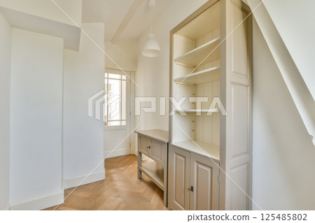 A sleek, modern interior featuring light-colored walls and a stylish cabinet, emphasizing simplicity and functionality in design. 125485802
