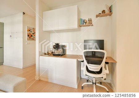 A sleek and modern home office setup featuring a stylish desk, ergonomic chair, and coffee machine enhancing productivity in a bright, minimalistic environment. 125485856