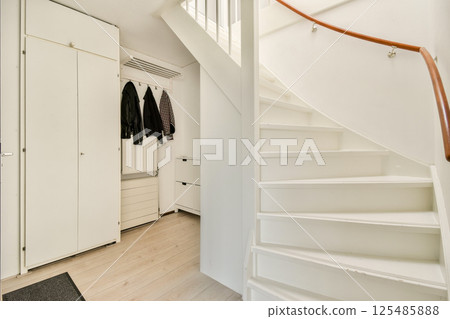A spacious modern interior featuring a white spiral staircase, wooden flooring, and minimalistic design elements. Ideal for contemporary home decor inspiration. 125485888