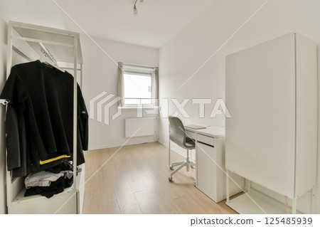 A bright and airy room featuring a simple desk, storage unit, and minimal decor. The clean lines create a serene and uncluttered workspace atmosphere. A bright and airy room featuring a simple desk, storage unit, and minimal decor. The clean lines create a serene and uncluttered workspace atmosphere. 125485939