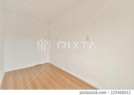 A clean and minimalist interior space featuring plain white walls and a wooden floor, exuding simplicity and openness. Ideal for modern decor concepts. 125486011