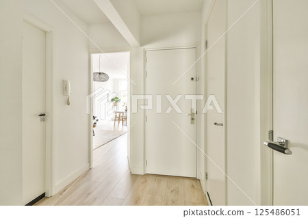 A bright and airy hallway showcasing a modern minimalist aesthetic with white walls and wooden flooring, inviting natural light into the space. A bright and airy hallway showcasing a modern minimalist aesthetic with white walls and wooden flooring, inviting natural light into the space. 125486051