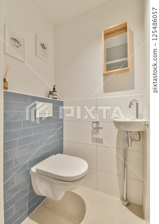 Sleek and contemporary bathroom featuring a minimalist toilet, stylish wall decor, and a compact washbasin, offering a fresh and clean aesthetic. Sleek and contemporary bathroom featuring a minimalist toilet, stylish wall decor, and a compact washbasin, offering a fresh and clean aesthetic. 125486057