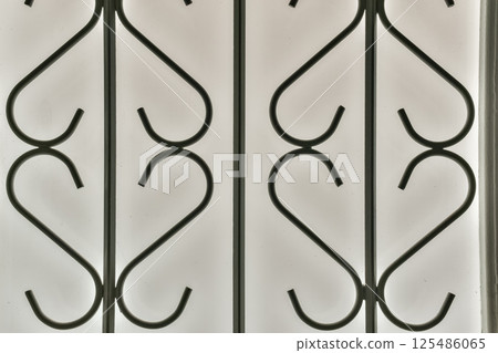 A detailed pattern of black metalwork against a translucent background, showcasing curves and elegance in design that enhances aesthetic appeal. A detailed pattern of black metalwork against a translucent background, showcasing curves and elegance in design that enhances aesthetic appeal. 125486065