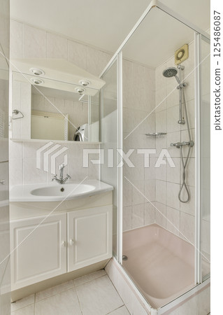 A stylish modern bathroom featuring a sleek shower area, elegant sink, and minimalist decor. The design emphasizes functionality and aesthetic appeal in a bright space. 125486087
