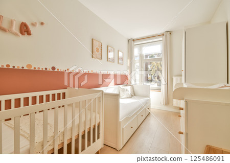 A serene nursery featuring a chic color palette, a comfortable crib, and large windows allowing natural light to fill the room. 125486091