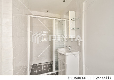 A sleek and functional modern bathroom featuring a walk-in shower, minimalist fixtures, and a clean aesthetic. Ideal for small spaces. 125486115