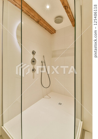 A sleek and modern shower design featuring glass doors, a handheld showerhead, and minimalist decor, perfect for contemporary bathrooms. 125486118