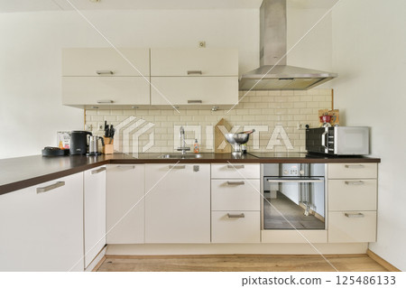 A well-designed modern kitchen featuring contemporary cabinetry, appliances, and an organized layout for efficient cooking and dining. A well-designed modern kitchen featuring contemporary cabinetry, appliances, and an organized layout for efficient cooking and dining. 125486133