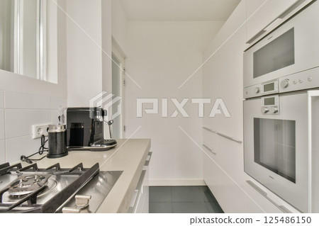 A sleek and minimalist kitchen featuring modern appliances, clean lines, and a contemporary design. Ideal for culinary enthusiasts and home decor. 125486150