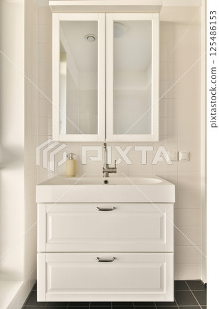 Sleek and minimalistic design of a modern bathroom vanity featuring a stylish sink and large mirror, perfect for contemporary home interiors. 125486153