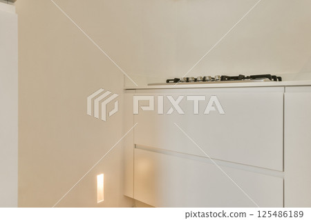 A sleek and modern kitchen featuring clean lines, minimalistic cabinets, and soft lighting, creating an inviting cooking space. The design emphasizes functionality and elegance. 125486189