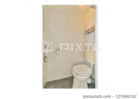 A compact bathroom featuring white tiled walls, a toilet, and a practical shelf for toiletries. The design emphasizes cleanliness and simplicity. 125486192