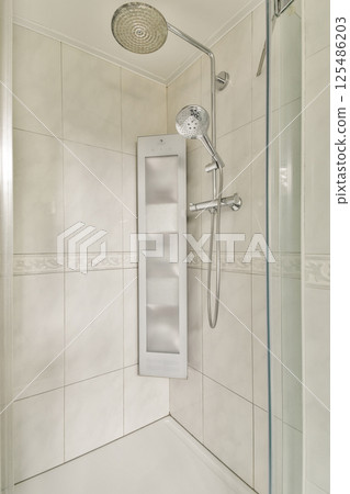 A sleek and contemporary shower setup featuring elegant tiles and modern fixtures that enhance a minimalist bathroom aesthetic. 125486203