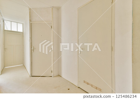 A spacious and minimalist interior hallway featuring white walls and doors, providing a clean and airy atmosphere for any home or office environment. A spacious and minimalist interior hallway featuring white walls and doors, providing a clean and airy atmosphere for any home or office environment. 125486234