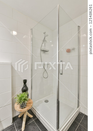 A sleek shower cabin with glass doors and minimalistic design creates a stylish focal point in a contemporary bathroom setting. A sleek shower cabin with glass doors and minimalistic design creates a stylish focal point in a contemporary bathroom setting. 125486261