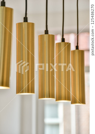Stylish pendant lights with a sleek gold finish illuminate a contemporary interior. Ideal for enhancing modern decor with a touch of elegance. Stylish pendant lights with a sleek gold finish illuminate a contemporary interior. Ideal for enhancing modern decor with a touch of elegance. 125486270
