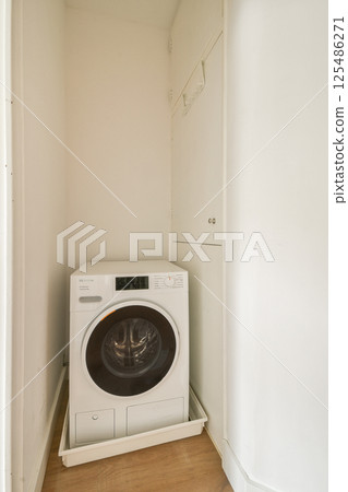 A sleek, modern washing machine positioned in a minimalist laundry space. The clean lines and neutral tones emphasize functionality and contemporary design. 125486271