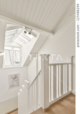 A clean and contemporary staircase featuring white walls and natural light, creating an airy and inviting atmosphere in the space. 125486294