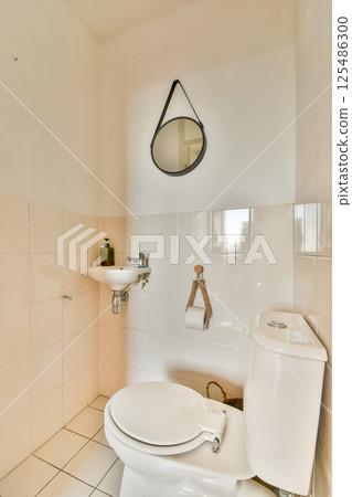 A clean and modern bathroom featuring essential fixtures like a toilet, sink, and mirror. The minimalist design emphasizes functionality and simplicity. 125486300