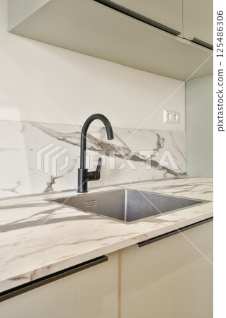 A sleek modern kitchen featuring a stylish black faucet, paired with elegant marble countertops that enhance the contemporary design. A sleek modern kitchen featuring a stylish black faucet, paired with elegant marble countertops that enhance the contemporary design. 125486306