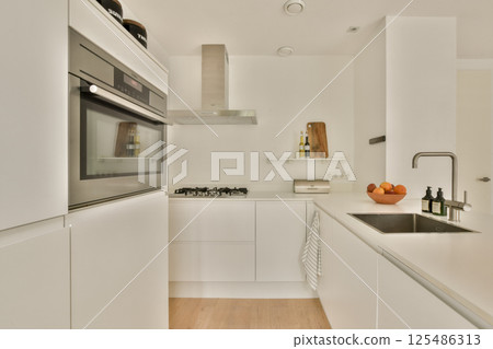 A sleek and modern kitchen showcasing minimalistic design with white cabinetry, integrated appliances, and clean lines. Perfect for contemporary spaces. A sleek and modern kitchen showcasing minimalistic design with white cabinetry, integrated appliances, and clean lines. Perfect for contemporary spaces. 125486313