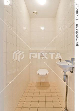 A clean and minimalist bathroom featuring white tiled walls, a simple toilet, and a small sink area, showcasing modern design principles. A clean and minimalist bathroom featuring white tiled walls, a simple toilet, and a small sink area, showcasing modern design principles. 125486324