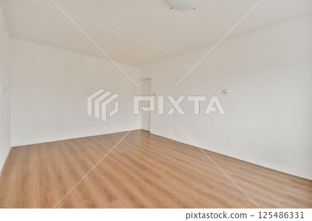 An uncluttered, minimalist interior featuring smooth wooden flooring, white walls, and a simple ceiling light, providing a serene atmosphere. 125486331