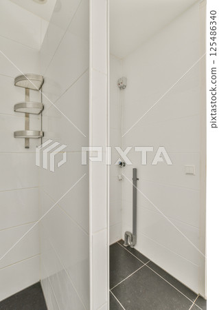 A sleek and minimalist design of a modern shower area featuring clean lines, glass walls, and dark flooring, perfect for contemporary bathrooms. 125486340