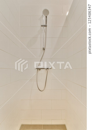 A clean and modern shower area featuring sleek white tiles and simple fixtures, emphasizing minimal design elements for a refreshing ambience. A clean and modern shower area featuring sleek white tiles and simple fixtures, emphasizing minimal design elements for a refreshing ambience. 125486347