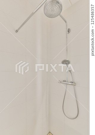 A sleek, contemporary showerhead displayed in a minimalist bathroom setting, emphasizing clean lines and modern design elements. 125486357