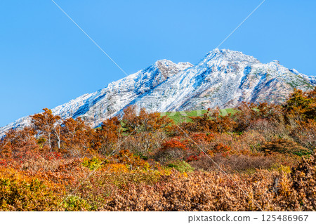 Mount Chokai, Yamagata - White snow-capped summit and autumn foliage at the base - 125486967